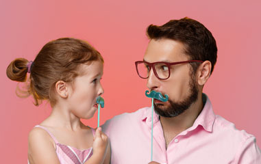 padre e hija haciendo caras con bigotes de cartón