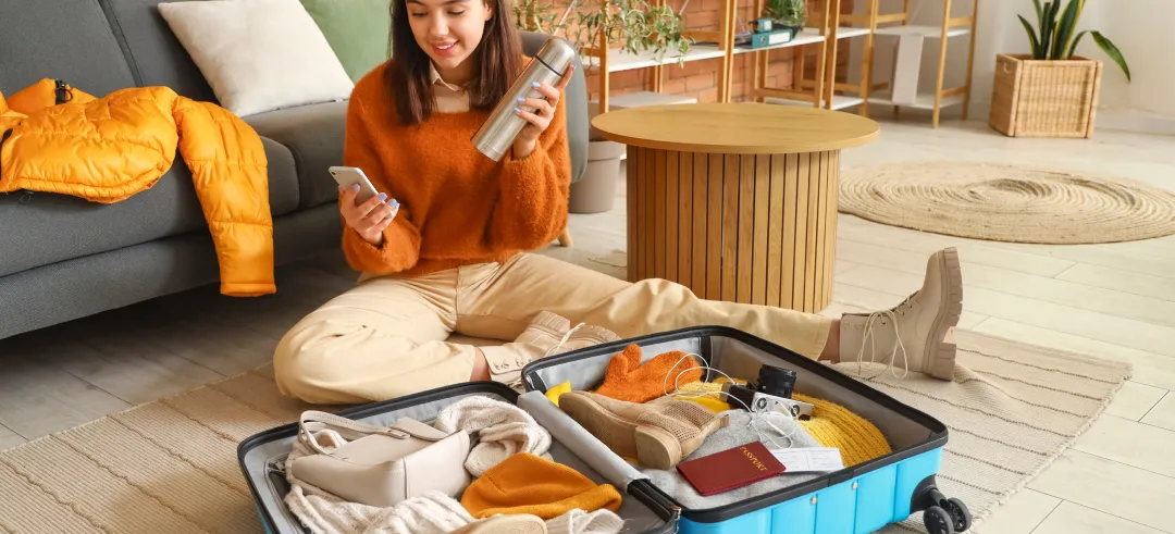 Mujer haciendo la maleta sentada en el suelo del salón
