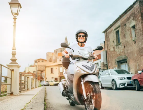 Mujer circulando con una motoneta por una ciudad