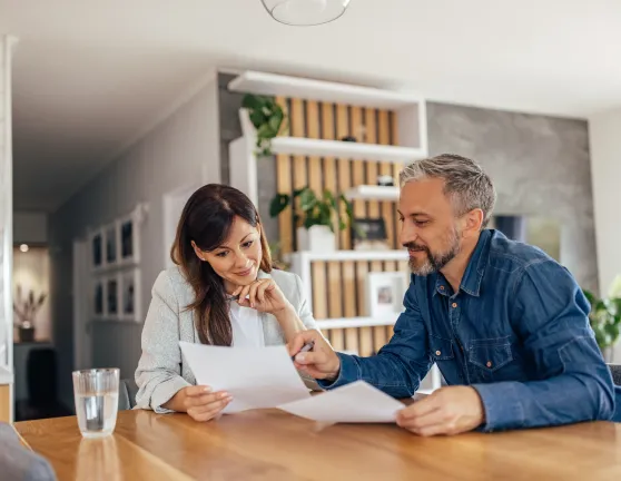 Pareja revisando documentos juntos sentados en el salón de una casa